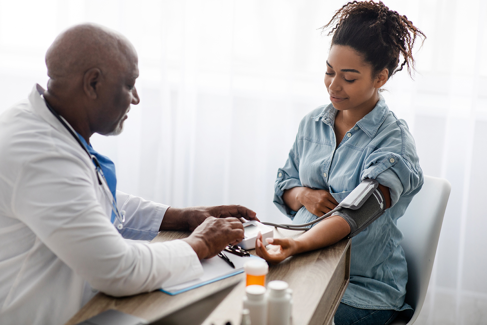 Black doctor checking blood pressure of pregnant patient