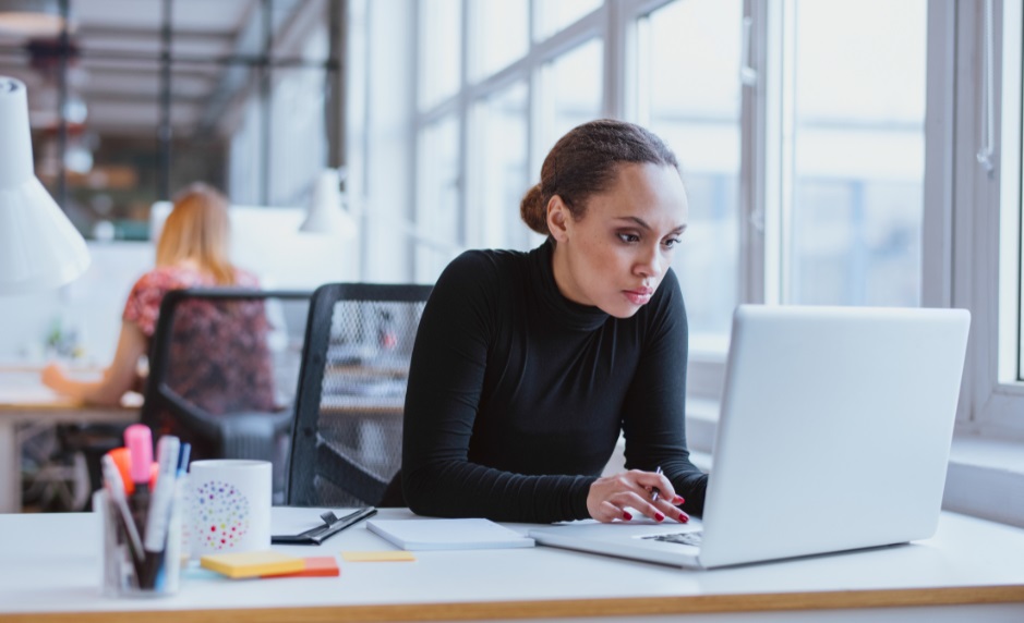 Woman looking intently at laptop computer as she works at her desk.