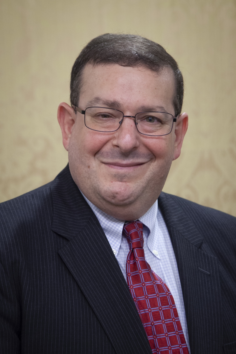 portrait of a white man wearing glasses and a suit and tie