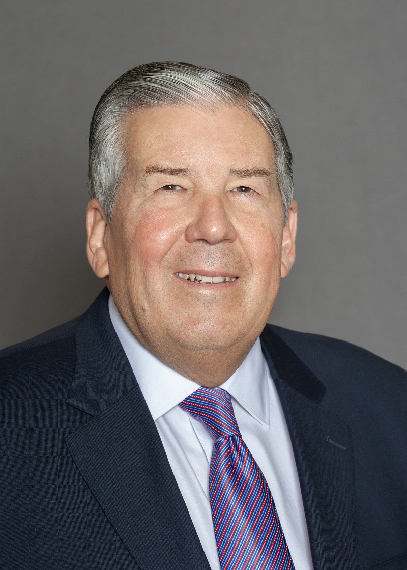 Portrait of a white male with silver hair in a suit and tie