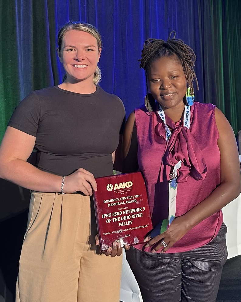 Two women are holding an award and smiling at the camera.